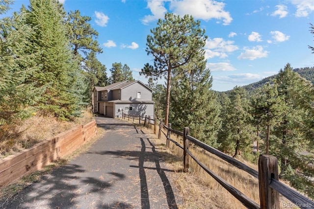 view of road featuring aphalt driveway and a wooded view