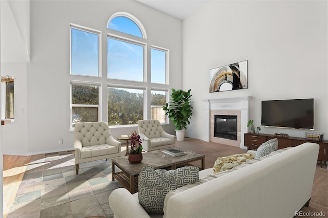 living area featuring baseboards, a tiled fireplace, and a towering ceiling