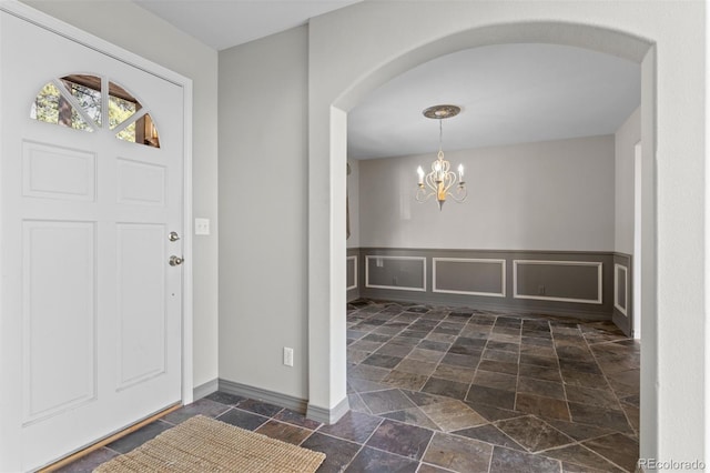 6904 Sprucedale Park Way, Evergreen, CO 80439 - foyer featuring stone tile flooring, a chandelier, arched walkways, and baseboards