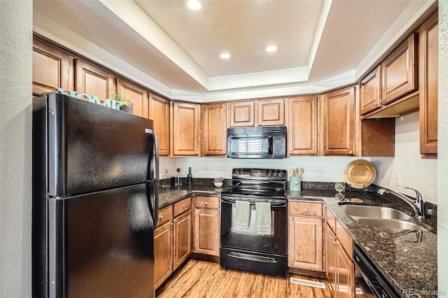 701 Harlan St Unit E59, Lakewood, CO 80214 - kitchen with brown cabinetry, a sink, a raised ceiling, black appliances, and light wood finished floors