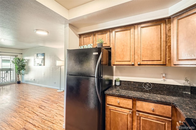 701 Harlan St Unit E59, Lakewood, CO 80214 - kitchen featuring baseboards, freestanding refrigerator, light wood finished floors, and brown cabinetry