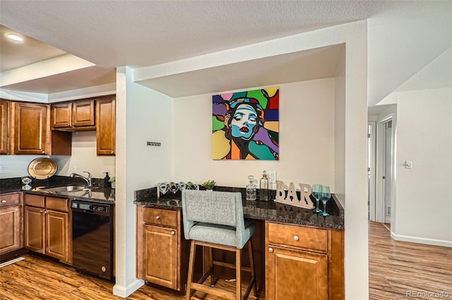 701 Harlan St Unit E59, Lakewood, CO 80214 - kitchen featuring wood finished floors, a sink, black dishwasher, and brown cabinets