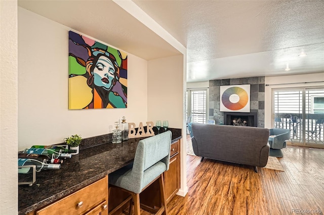 701 Harlan St Unit E59, Lakewood, CO 80214 - living area with a healthy amount of sunlight, a textured ceiling, wood finished floors, and a tile fireplace