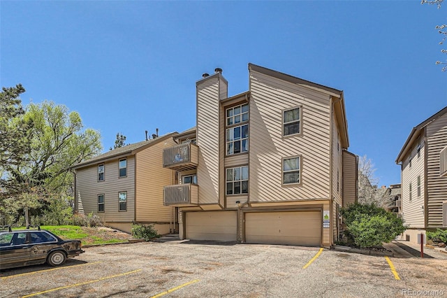 701 Harlan St Unit E59, Lakewood, CO 80214 - view of front of house with uncovered parking, a chimney, and a garage