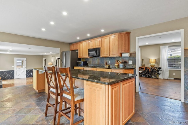 kitchen featuring black microwave, plenty of natural light, a center island, recessed lighting, and stone tile floors