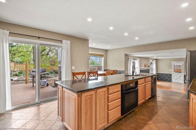 kitchen with black oven, a sink, recessed lighting, a kitchen island with sink, and dishwasher