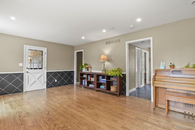 foyer featuring wood finished floors, wainscoting, recessed lighting, and tile walls