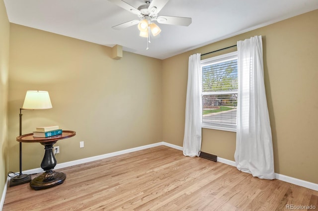 spare room with light wood finished floors, baseboards, and ceiling fan