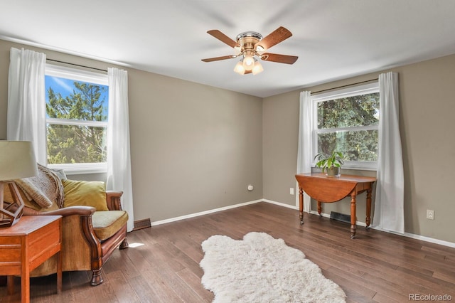 living area with a ceiling fan, wood finished floors, and baseboards