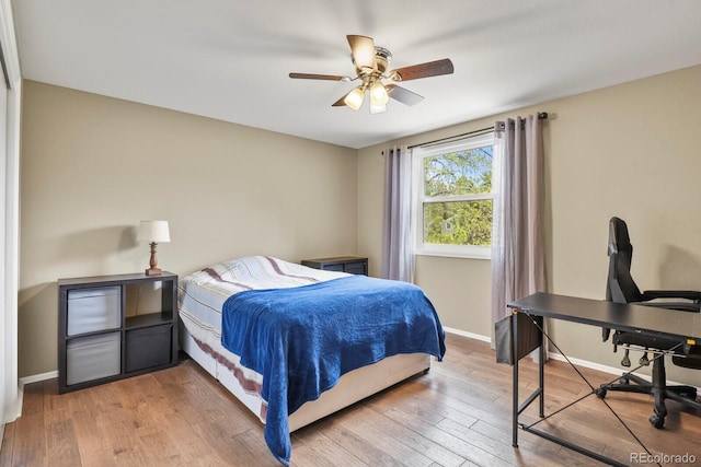 bedroom featuring baseboards, a desk, hardwood / wood-style floors, and ceiling fan