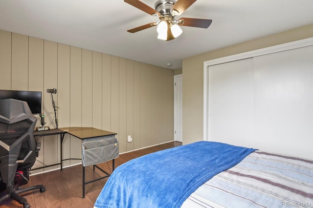 bedroom featuring wood finished floors, an office area, a closet, and a ceiling fan