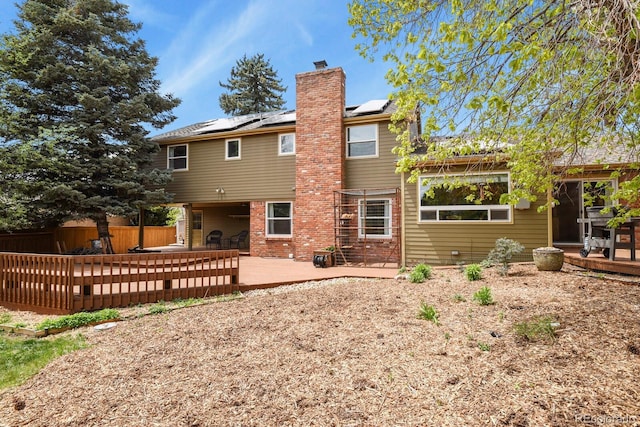 back of house featuring solar panels, a chimney, a patio, a fenced backyard, and brick siding