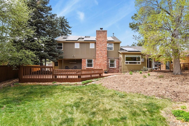 back of property featuring a chimney, solar panels, a wooden deck, and a patio