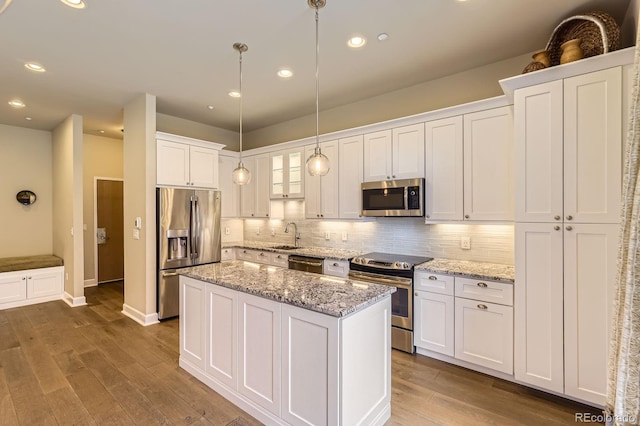5677 S Park Pl Unit A308, Englewood, CO 80111 - kitchen featuring stainless steel appliances, white cabinetry, backsplash, a center island, and wood finished floors