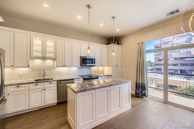 5677 S Park Pl Unit A308, Englewood, CO 80111 - kitchen with appliances with stainless steel finishes, dark wood finished floors, decorative backsplash, white cabinets, and recessed lighting