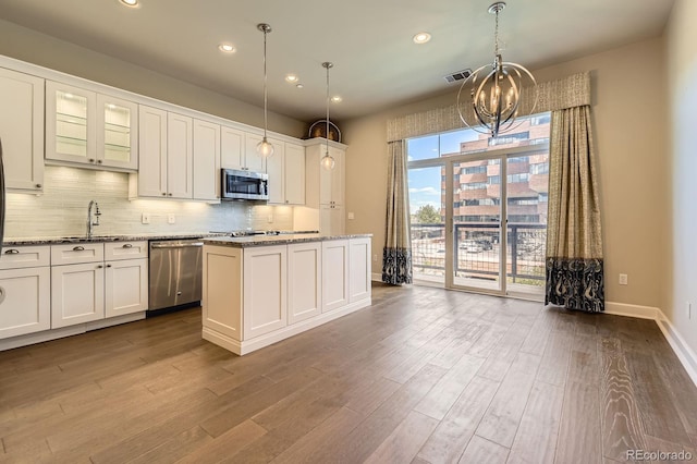 5677 S Park Pl Unit A308, Englewood, CO 80111 - kitchen featuring appliances with stainless steel finishes, a chandelier, decorative backsplash, dark wood-type flooring, and light stone countertops
