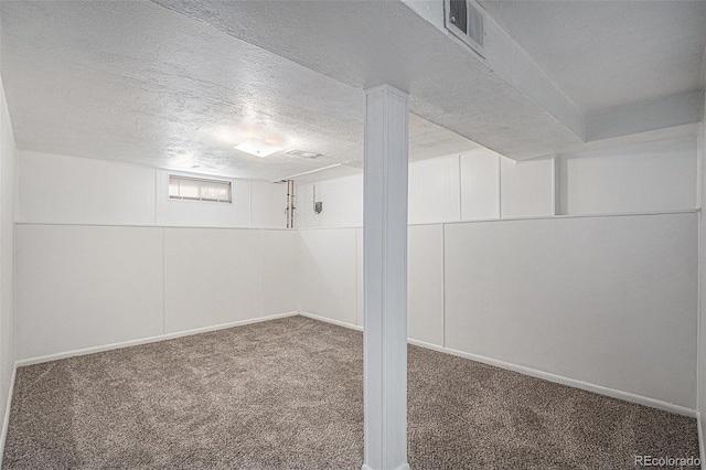 basement with visible vents, a textured ceiling, and carpet flooring