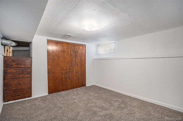 finished basement with baseboards, visible vents, carpet floors, and a textured ceiling