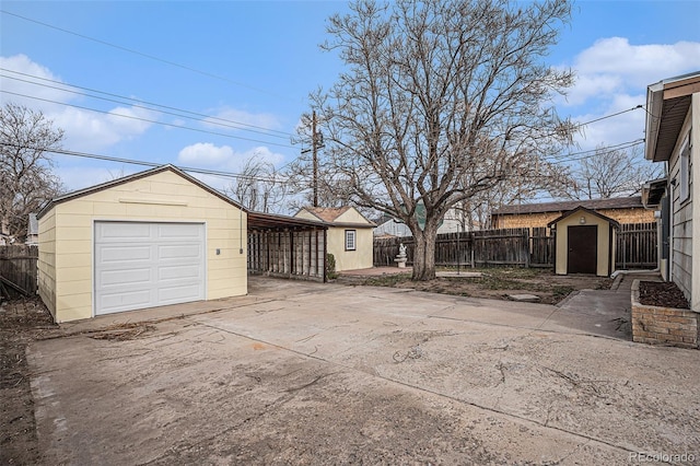 garage with driveway, a storage shed, a garage, and fence