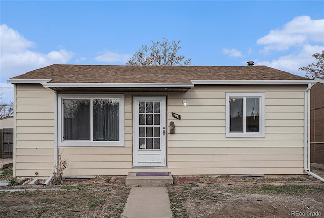 bungalow-style house featuring a shingled roof and fence