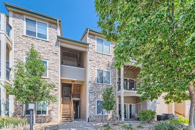 7409 S Alkire St Unit 304, Littleton, CO 80127 - view of front of house featuring stone siding, stairway, central AC unit, and a balcony