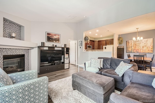 7409 S Alkire St Unit 304, Littleton, CO 80127 - living area featuring a chandelier, wood finished floors, lofted ceiling, and a tiled fireplace