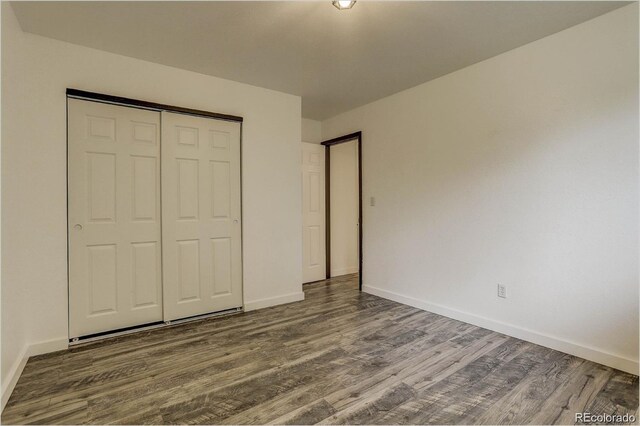 unfurnished bedroom with a closet and dark wood-type flooring