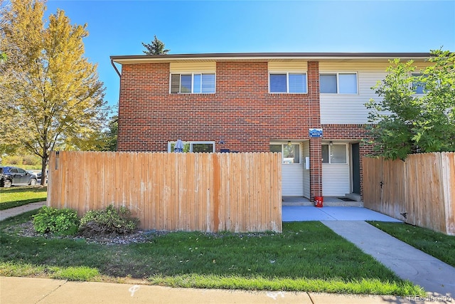 view of front of home with brick siding, fence, and a front yard