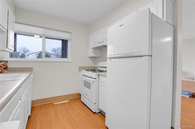 kitchen featuring under cabinet range hood, light wood-style flooring, white appliances, and white cabinetry