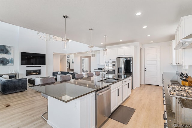 kitchen with stainless steel appliances, light wood-style flooring, white cabinetry, and a sink