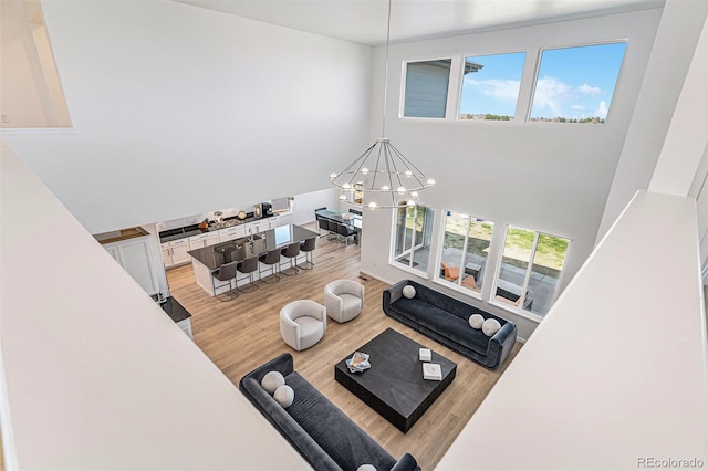 living area with a towering ceiling, light wood-style floors, and an inviting chandelier