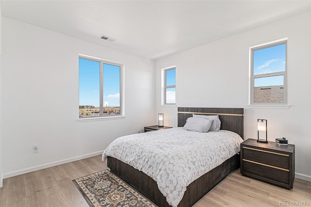 bedroom with visible vents, baseboards, and light wood finished floors