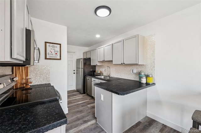 647 Berwick Ave, Firestone, CO 80520 - kitchen with dark wood-style floors, decorative backsplash, a peninsula, dark countertops, and recessed lighting