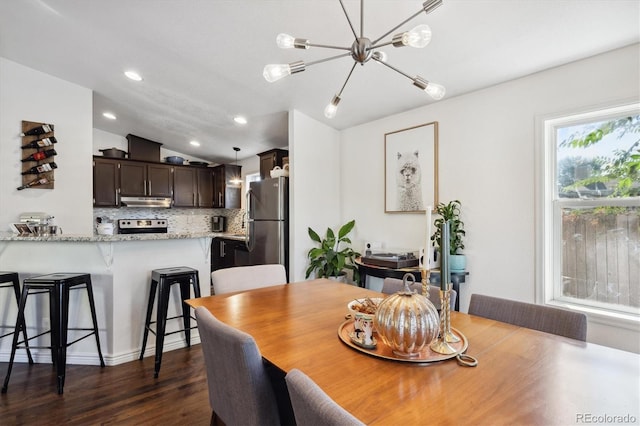 dining room with dark wood-type flooring, vaulted ceiling, and a notable chandelier