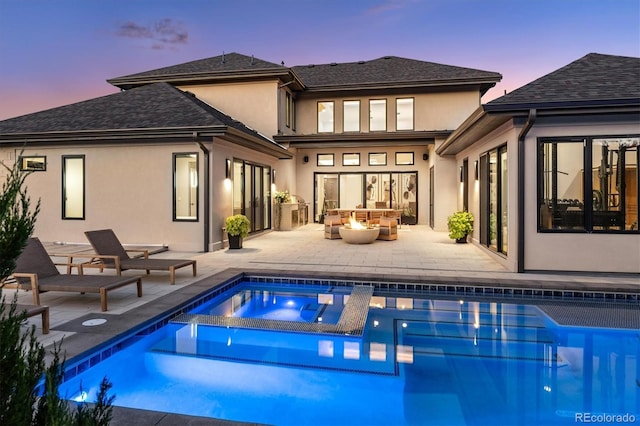 rear view of house featuring an outdoor pool, a patio area, an outdoor living space with a fire pit, and stucco siding