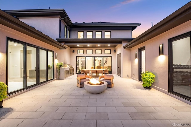 patio terrace at dusk with a fire pit and area for grilling