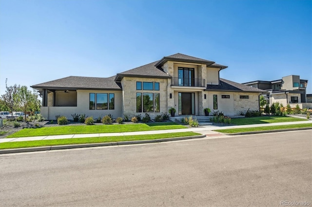 prairie-style home with stone siding, a front lawn, and stucco siding