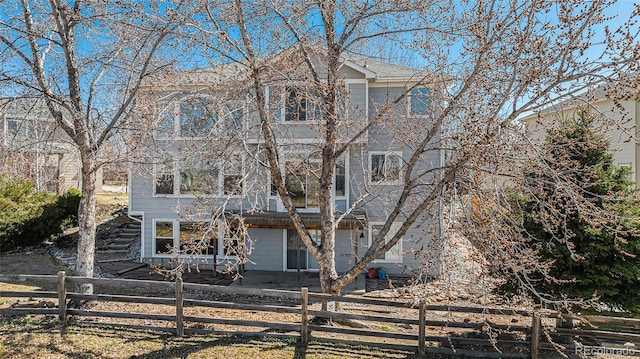 rear view of property with a fenced front yard and stairway