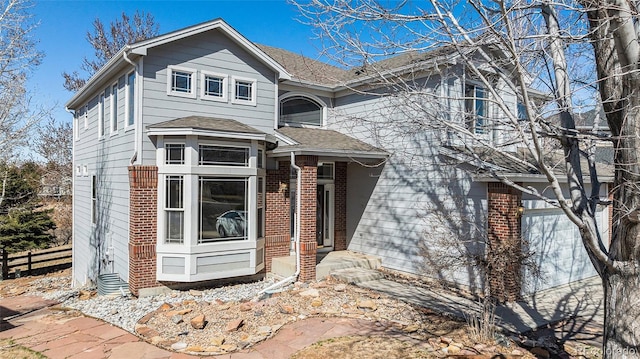 view of front of property featuring an attached garage, fence, brick siding, and roof with shingles