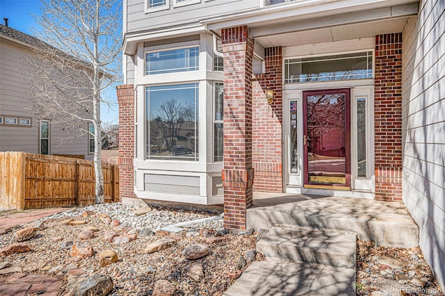 entrance to property with brick siding and fence