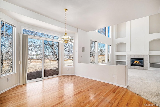 unfurnished dining area with visible vents, built in features, light wood finished floors, baseboards, and a chandelier