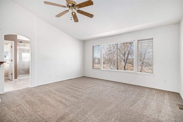 spare room featuring visible vents, a ceiling fan, arched walkways, light colored carpet, and vaulted ceiling