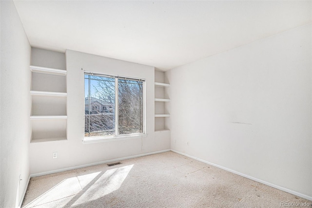 spare room with built in features, visible vents, baseboards, and carpet