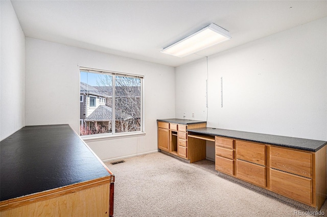 office area featuring light colored carpet, visible vents, and built in desk