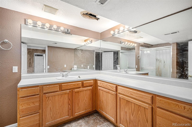 bathroom with vanity, visible vents, a stall shower, tile patterned floors, and a textured wall