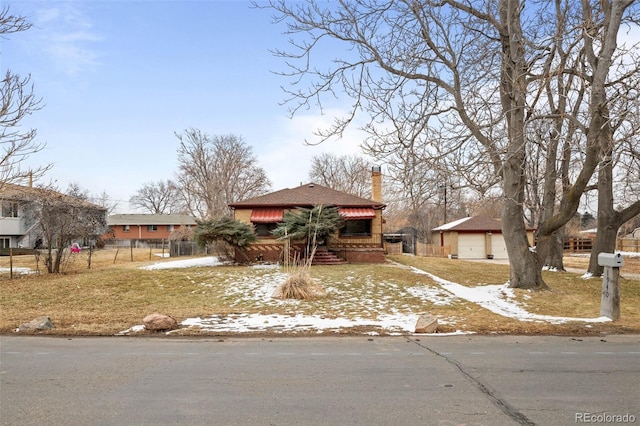 view of front of home with a chimney, a detached garage, and fence