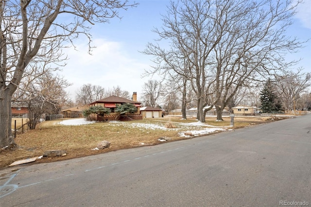 view of front facade featuring a garage, a chimney, fence, and a residential view