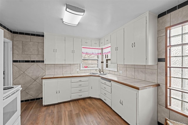 kitchen with a sink, tile walls, white cabinets, tile counters, and white electric range oven