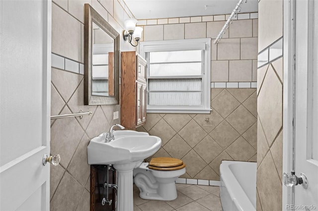 full bath with a tub to relax in, toilet, tile walls, and tile patterned floors