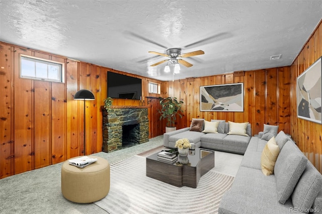 living room with a textured ceiling, carpet floors, a fireplace, and wooden walls